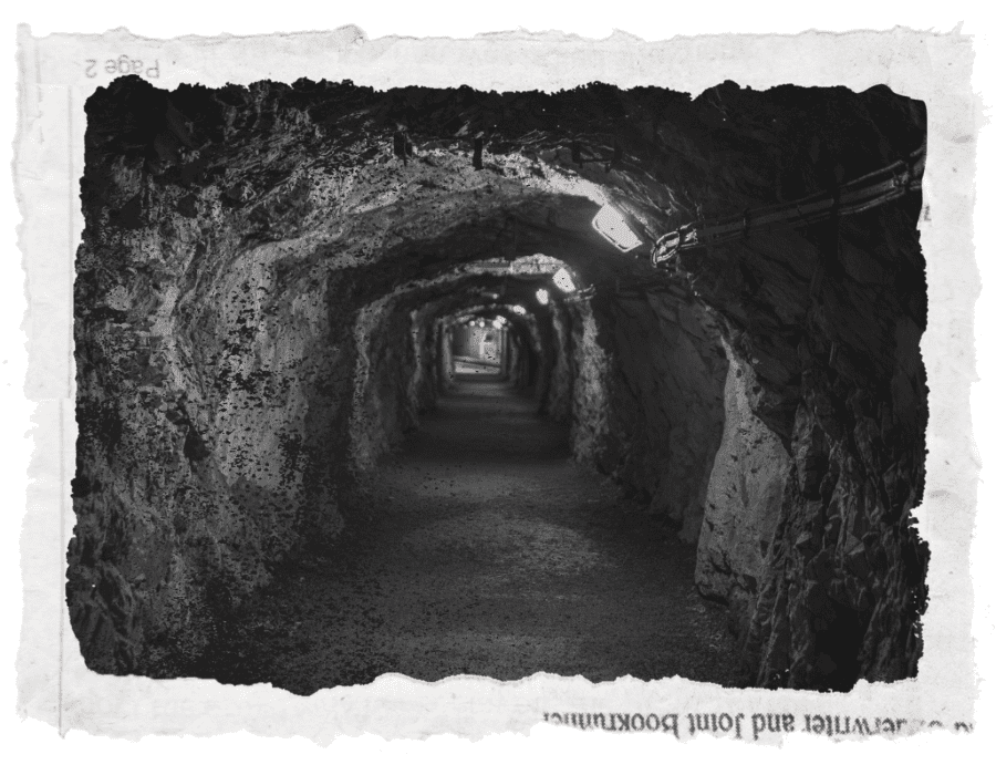 A coal mine tunnel in black and white in a ripped up newspaper frame