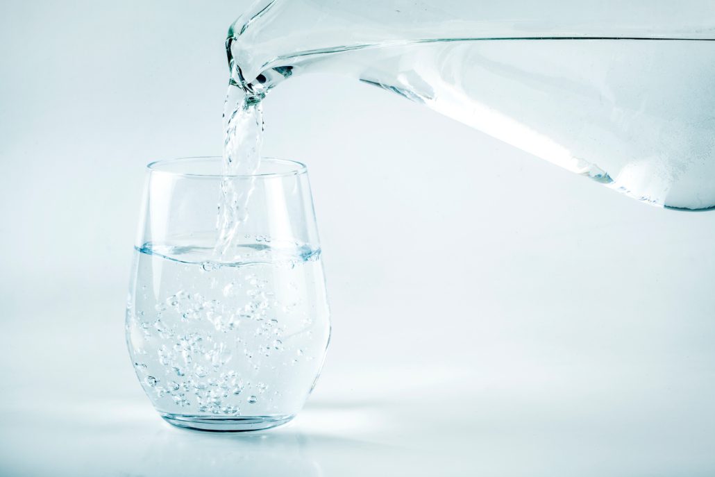 A jug of water being poured into a glass