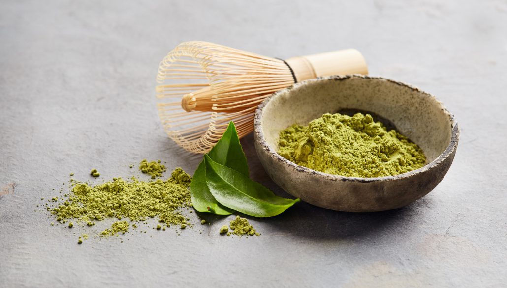 A bowl with a whisk and matcha powder in the bowl