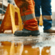 two men in hivis trousers standing on wet floor with a caution wet floor sign