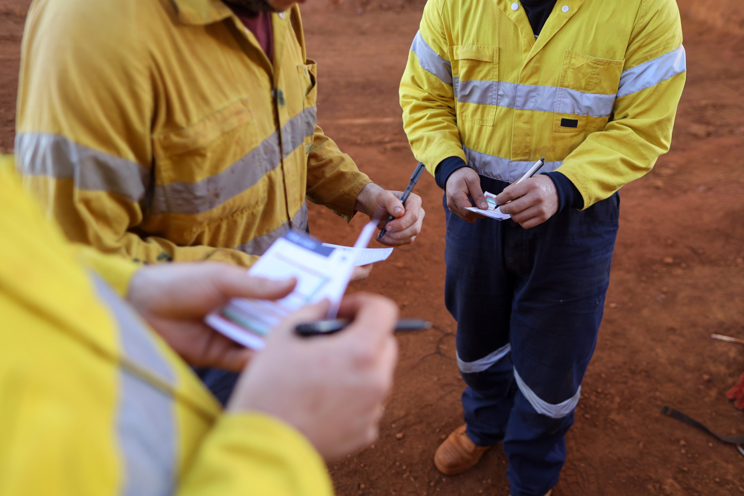 Side picture of worker are conducting writing self personal pre risk assessment knowing as take five or taking control step on the boolet prior to work of each task a group of men in yellow jackets carrying out risk assessment