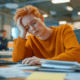 Young woman in an orange sweater looks exhausted at her desk in a busy office, AI